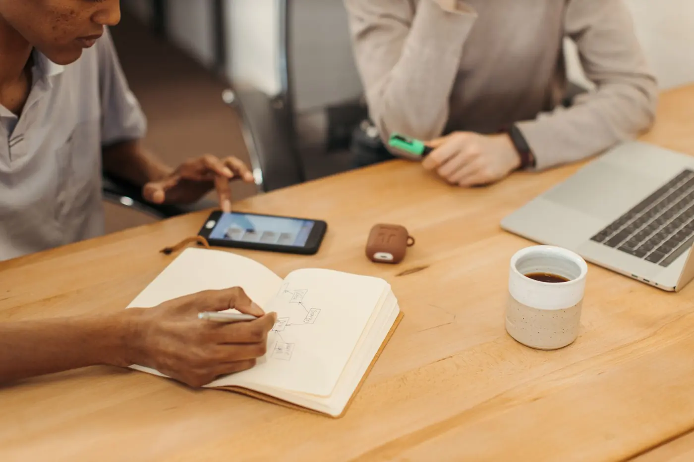 Une graphiste écrit dans un carnet à côté de son téléphone