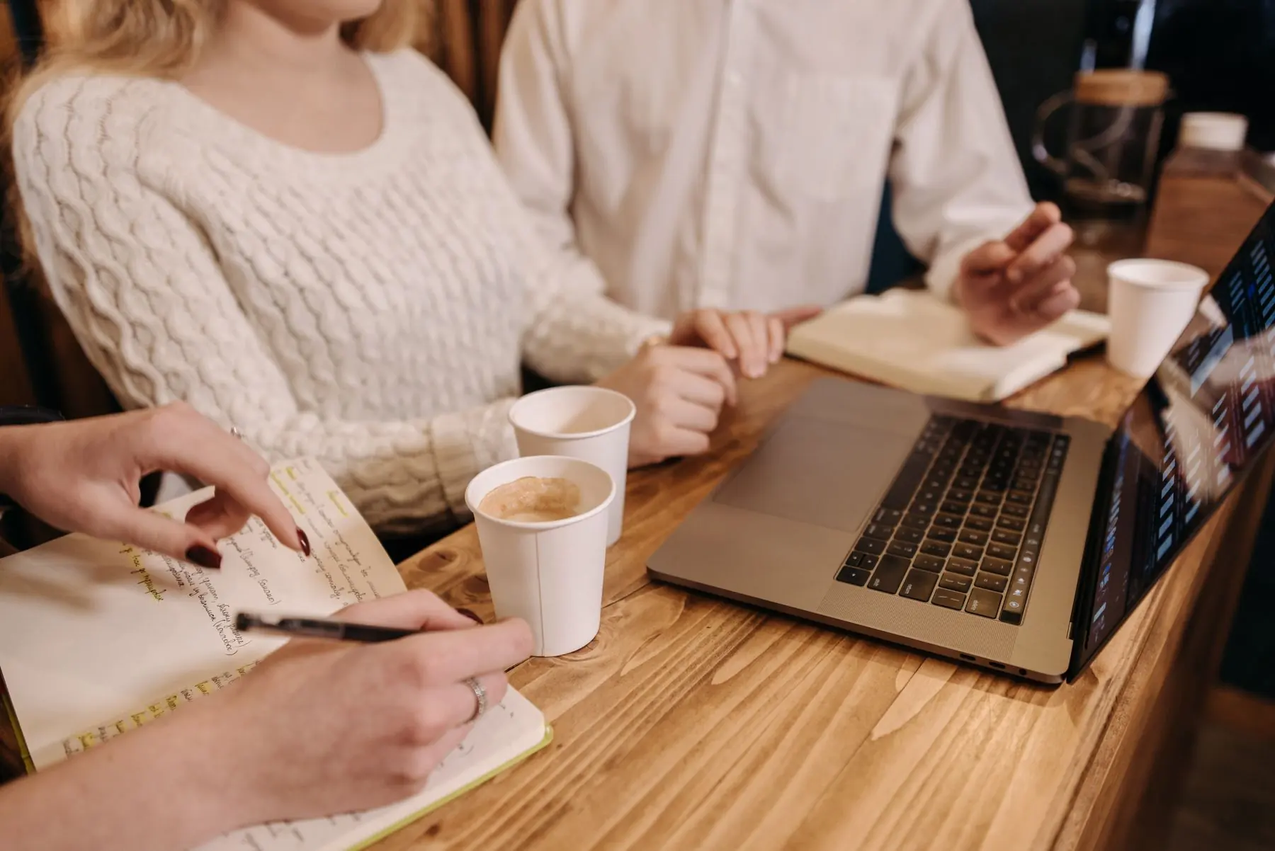 Des entrepreneurs prennent des notes autour d'une table en bois, café à la main